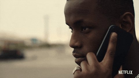 The image features a man talking on his cell phone while standing outside next to a vehicle, likely a car or truck. The text around the edges of the image refers to various unrelated topics such as saying less, increasing prices, bank protocols, and lending money. However, these pieces of information are not relevant to the main scene, which is focused on the man talking on his cell phone in front of a vehicle.
