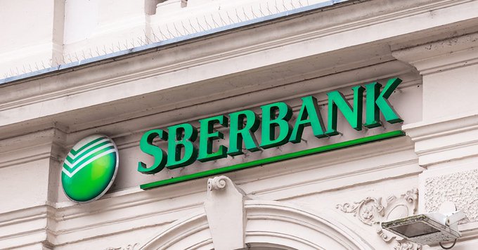 The green logo and name of 'SBERBANK' are mounted on the white architectural facade of a building.