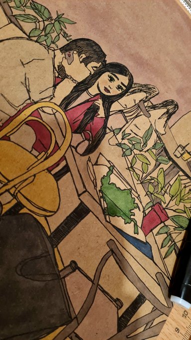 A close-up photograph of a tattoo on skin depicting a stylized illustration of two figures among plants and chairs with green leaves and pink details.