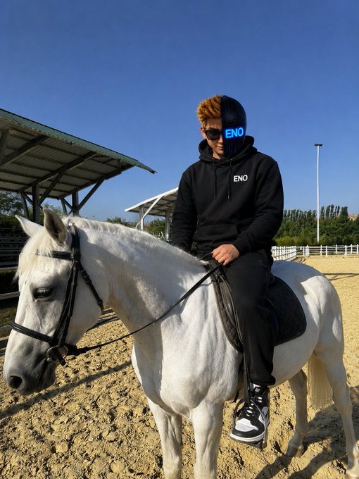 A young person with blonde hair wearing a black "ENO" hoodie and sunglasses rides a white horse in a sandy outdoor arena, embodying the message of starting fresh with discipline and consistency as the sun rises on a new day in CT.