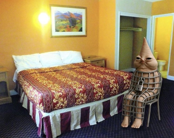 A bizarre, caged creature resembling a nose sits in a motel room next to a bed, mirroring the post's theme of an undervalued opportunity like "$QENIS" being "under the radar" and awaiting attention.
