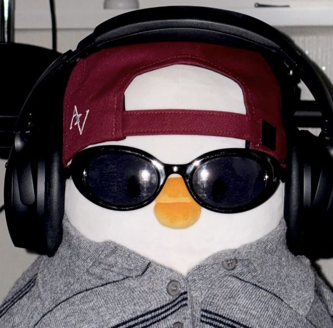 A plush snowman toy wearing a maroon backwards cap, black oval sunglasses, large black headphones, and a grey polo shirt.