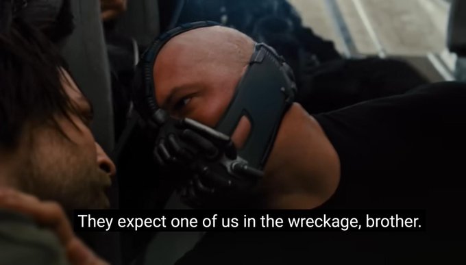 A scene from a movie showing Bane in his mask with the subtitle 'They expect one of us in the wreckage, brother.'