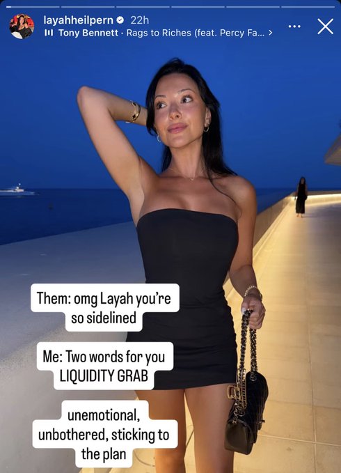 The image shows an Instagram story from user "layahheilpern" featuring a woman in a black strapless dress posing by the water at dusk, with Tony Bennett's "Rags to Riches" playing in the background. Overlaid text reads: "Them: omg Layah you're so sidelined / Me: Two words for you LIQUIDITY GRAB / unemotional, unbothered, sticking to the plan," reflecting the post's caption about remaining detached from market manipulation.