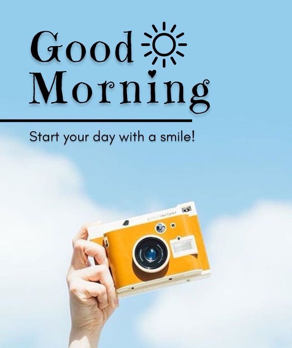 A cheerful morning graphic featuring the text "Good Morning" with a sun and heart icon, and the subtitle "Start your day with a smile!" against a blue sky, with a hand holding an orange and white instant camera below.