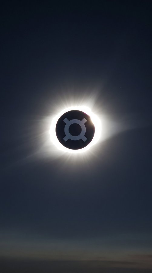 A dramatic photograph captures a solar eclipse, with a dark circular silhouette displaying a white planetary symbol set against the bright, glowing corona of the sun in a dark sky.