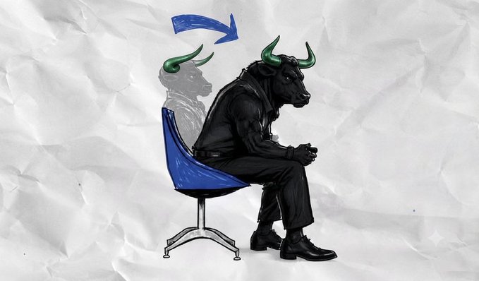 A black bull with green horns sits hunched on a blue chair, staring dejectedly with a faded ghost-like version of itself above and a blue arrow pointing to it. The image visually conveys the post's theme of a defeated or deflated reaction when "$ANSEM" is mentioned, mirroring the slumped posture of the bull market.