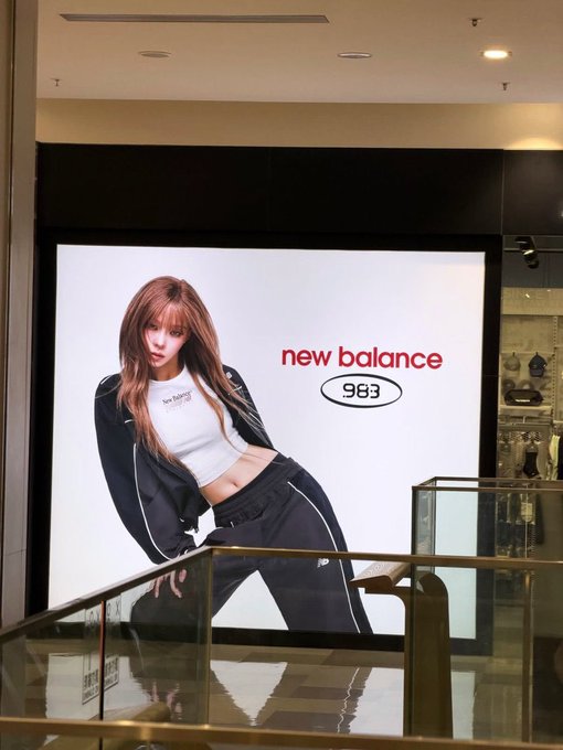 An advertisement for 'new balance 983' features a woman in black athletic wear posing, visible inside what looks like a store or mall.