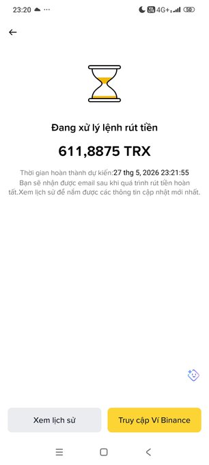 The image shows a phone screen with an app called "Trx" displayed at the top of the screen. The app has a yellow icon, which is a clock or hourglass symbol. Below this icon, there are two lines of text written in Vietnamese that read "Dýng xiên trình không các bắt đầu hành trình mua 100$ TRX." The phone screen also displays a message from the app, which says "This year you have won 5 Bitcoins. Click here to claim your prize."