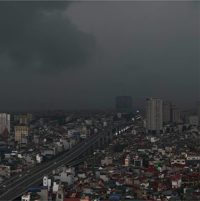 The caption for this image might read: "Gloomy Skies Over a Sleeping City by a Bridge." The accompanying post, written in Vietnamese, translates to a person's evening reflection after a day at work, expressing a casual account of their routine and thoughts about cryptocurrency, along with their weekend plans and light-hearted comments about their lifestyle and work challenges. The image complements the post by visually representing the "gloomy" sky mentioned in the text, reflecting the mood of the speaker's end-of-day contemplation.