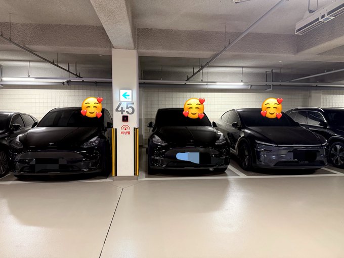 Three black cars are parked in an underground parking garage at spots 45, 46, and 47, each marked with smiling face-with-hearts emoji stickers over their windshields.