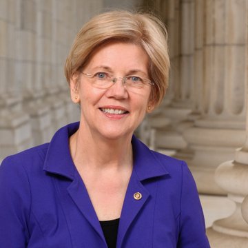 The photo shows Senator Elizabeth Warren, a blonde woman wearing glasses and a purple blazer, smiling in front of classical stone columns. The image accompanies the news that she supports crypto legislation but opposes the CLARITY Act, which she criticizes as being written by the crypto industry to benefit itself.