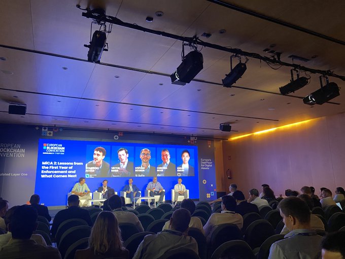 A panel discussion at the European Blockchain Convention titled "MiCA 2: Lessons from the First Year of Enforcement and What Comes Next," featuring speakers Esenyuva (CEO, SkyBridge), Visce (Founder), Diniz (Sensible), Bonet (CEO), and Abruzzini, addressing topics related to blockchain regulation and real-world asset interoperability.