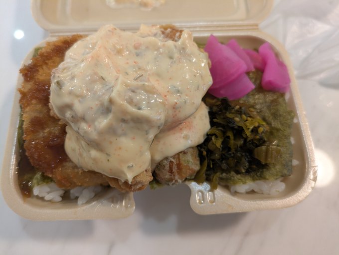 A bento box featuring crispy fried chicken (karaage) smothered in a creamy tartar-style sauce over rice, accompanied by seasoned seaweed greens and pickled pink ginger. The image embodies the post's call to action, presenting a hearty, balanced meal ready to "strike" against societal dilemmas through its bold, satisfying presentation.
