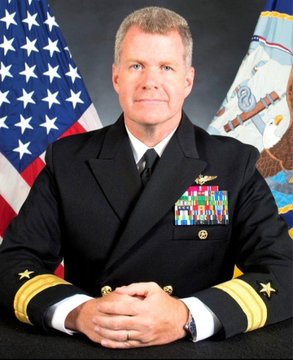 A formal military portrait shows Admiral Samuel Paparo in his Navy dress uniform adorned with numerous service ribbons and insignia, with the American flag and Navy flag displayed behind him. The image accompanies a post highlighting his recent revelation that the U.S. military is testing Bitcoin's decentralized infrastructure for securing and protecting networks beyond financial applications.