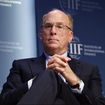 Larry Fink, CEO of BlackRock, sits with his hands clasped at the Institute of International Finance (IIF) podium.
