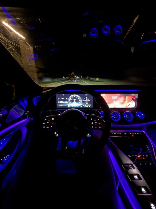 The image shows the interior of a luxury car at night, featuring a Mercedes-Benz dashboard illuminated with ambient blue lighting, digital gauges, and an infotainment screen displaying the time "7:11". The post's caption "It's a beautiful Friday with opportunity in front of us" paired with this image evokes a sense of luxury, drive, and forward momentum—symbolizing ambition and the pursuit of financial success through active engagement and opportunity-seeking.
