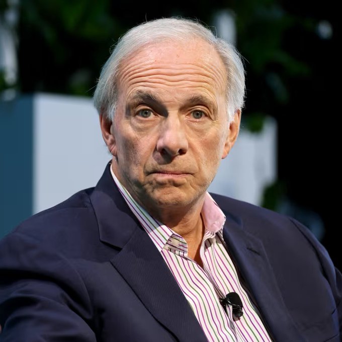 Ray Dalio, the billionaire founder of Bridgewater Associates, sits on stage at an event with a serious expression, visually anchoring a warning about an impending U.S. debt crisis within three years if federal deficits aren't reduced from 6% to 3% of GDP.
