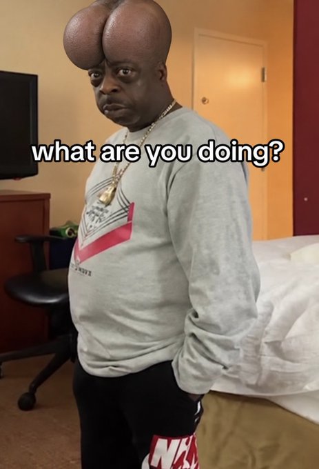 A man wearing a gray sweatshirt with cartoonish testicles over his head asks "what are you doing?" in a hotel room.