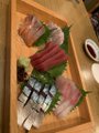 iced tea and a small plate of sushi are arranged on a wooden tray, accompanied by a small bowl of green sauce.