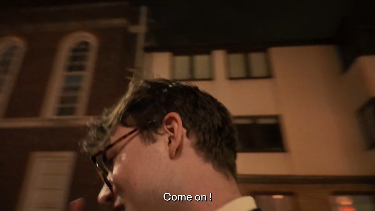 A man with glasses is shown in profile against a nighttime backdrop of brick buildings, with the subtitle "Come on!" displayed at the bottom. The caption "Come on!" reflects his enthusiastic energy as he enjoys an evening out, tying into the post's excitement about the fun time spent with the mentioned individuals.
