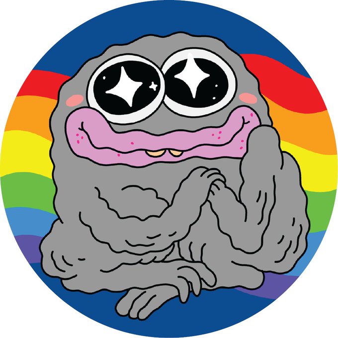 A cartoon gray monster character with large sparkly eyes, pink lips, and small fangs sits against a colorful rainbow circular background.