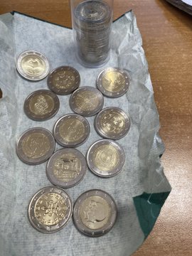 A collection of Canadian coins, including several two-dollar "toonies," arranged on a paper towel next to a rolled stack of coins.
