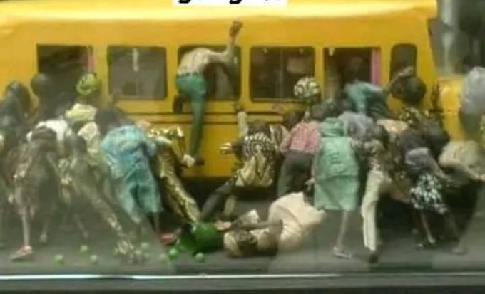 A large crowd of children in school uniforms swarm a yellow bus, climbing in through windows and doors in a chaotic scene.