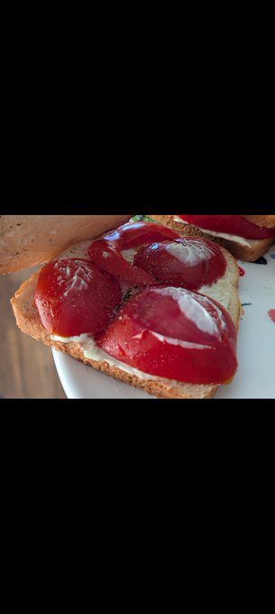 A close-up of toast topped with cream cheese and bright red strawberry slices, served on a white plate.