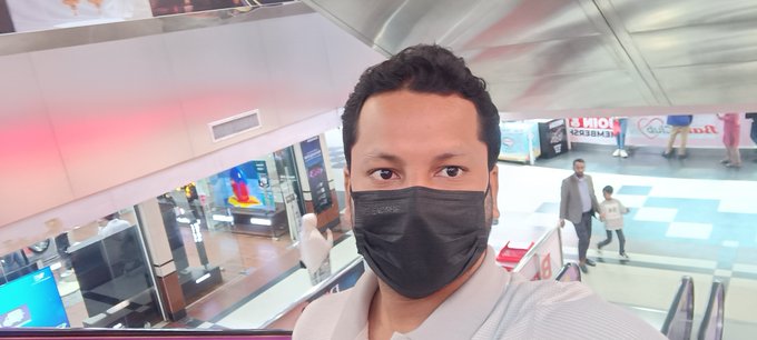 A man wearing a black face mask takes a selfie in what appears to be a shopping mall, with a "THE NETWORK" sign visible in the background, matching the morning greeting and networking-related tags in the post.