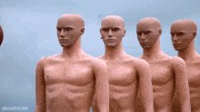 This image features a group of mannequins standing close together against a blue backdrop, with five of them positioned straight ahead and another placed behind them. The positioning of the mannequins suggests that they are arranged for a specific display or promotional event.