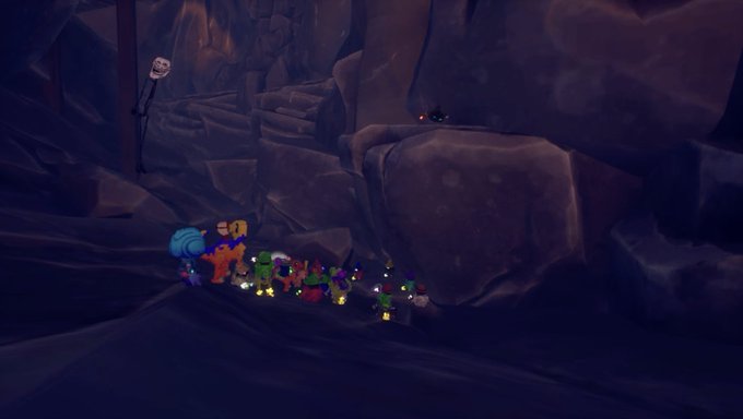 The image features a group of people standing around, with some of them holding backpacks or handbags. The scene takes place in an area that appears to be a cave or a mountain range, giving off a spooky atmosphere. There are at least 13 people visible in the image, and they seem to be gathered together for a specific purpose or event.