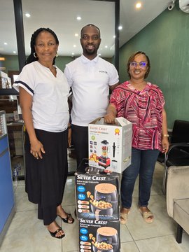 Three people pose together holding boxes of 'Silver Crest' appliances in what appears to be a store setting.