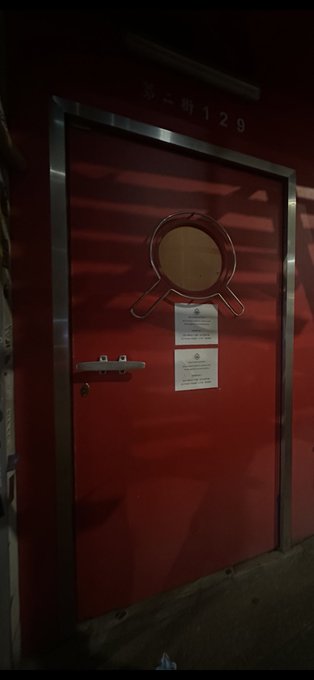A red metal door marked "第二街 129" (Second Street 129) features a circular window and posted notices, serving as the striking entrance to the BAYC HK (Bored Ape Yacht Club Hong Kong) venue — a fitting "Door to the Future" for the exclusive event.