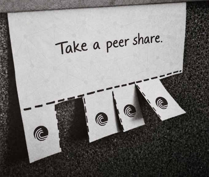A sign reading 'Take a peer share.' hangs on a wall with four tear-off tabs below, each featuring a circular logo, suggesting a clever play on 'peer-to-peer' sharing.