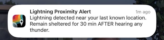 A smartphone notification reading 'Lightning Proximity Alert — Lightning detected near your last known location. Remain sheltered for 30 min AFTER hearing any thunder.'