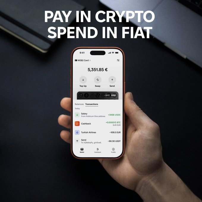 The image shows a person's hand holding an iPhone displaying a cryptocurrency wallet app that allows users to pay with Bitcoin or TON instantly, without any delays or complications. The user can easily send money through the app using their credit card or other payment methods. This feature is particularly useful for people who want to quickly and securely transfer funds between accounts or make purchases online.