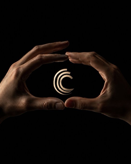 Two hands cupped in darkness cradle a small glowing logo composed of three curved arcs resembling a stylized 'C'.