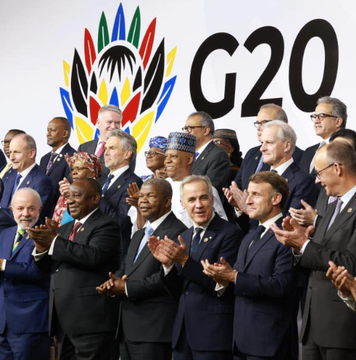 World leaders, including Emmanuel Macron and Cyril Ramaphosa, gather at a G20 summit, clapping together beneath the iconic G20 logo, as finance ministers and central bank governors commit to advancing responsible frameworks for digital asset innovation.