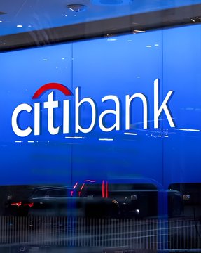 The image shows a Citi bank branch sign with the distinctive Citibank logo featuring its signature red arc over the blue and white lettering. The accompanying post highlights a major partnership between Citigroup and Coinbase, emphasizing Citi's role in enabling stablecoin payments across a vast portion of global eCommerce—visually grounding the financial giant at the center of this crypto-finance development.