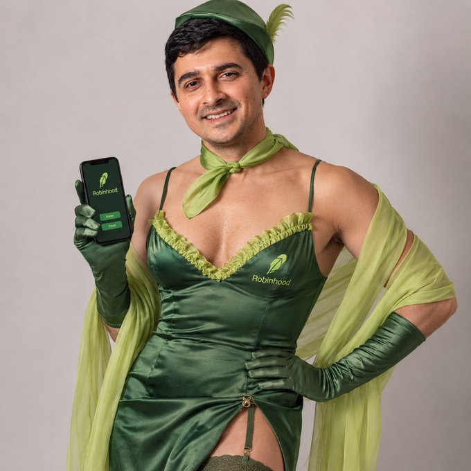 The same man in the green Robinhood-themed costume with a feathered hat and corset dress, holding a phone showing the Robinhood app.
