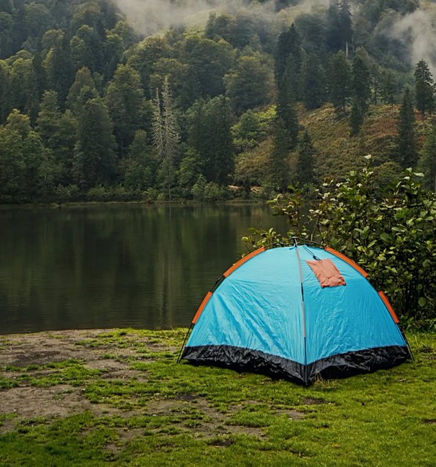 A bright blue dome tent is pitched on a grassy lakeshore, with calm waters and a misty, tree-covered mountainside in the background. The scene captures a peaceful outdoor escape, reflecting the post's message of taking time to enjoy yourself with $SUI $WAL.