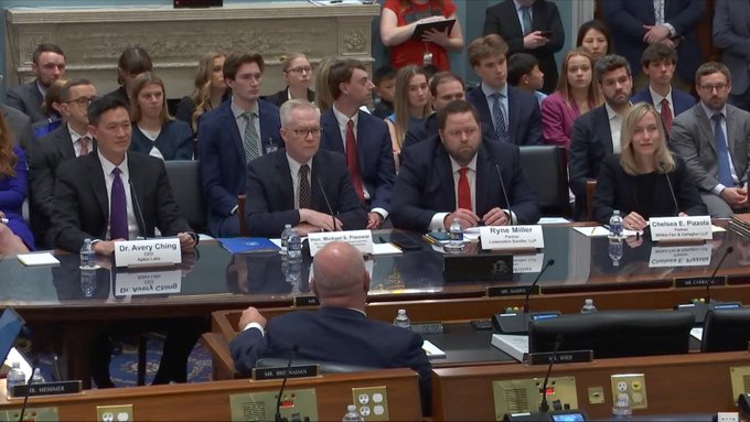 The image shows a group of people sitting at desks, engaged in a meeting or conference. There are several men wearing suits and ties, suggesting that they might be participating in a formal event or discussion. The room has multiple TVs mounted on the walls, which could be used for presentations or displaying relevant information during the meeting.

The image also contains text that reads "A year later, the infrastructure @AveryChing described to Congress is live and scaling fast on @Aptos .", indicating a connection between the image and the post about the infrastructure in the US. The focus of this post seems to be on the current state of the infrastructure and its impact on real markets.