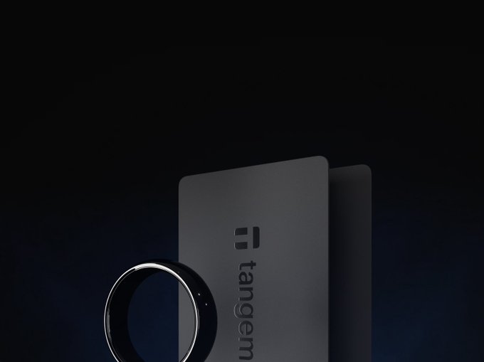 A dark, sleek product render of a Tangem hardware crypto wallet with a ring device in the foreground.