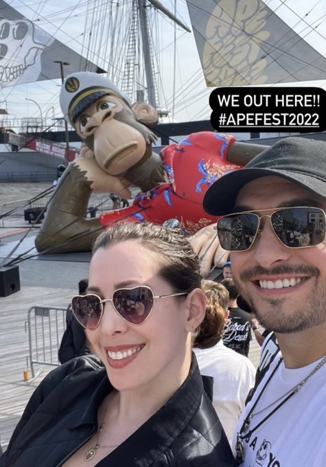 The image features a man and woman posing for a photo with a large inflatable monkey sculpture as their backdrop. They are both smiling, indicating that they are enjoying themselves. The text "Take me back to.. ApeFest 2022" is present in the image, suggesting that this event might be related to an Ape Festival or some other similar gathering.

The couple appears to be dressed for a special occasion and wearing sunglasses, which adds to the festive atmosphere of the photo.