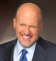 Headshot portrait of a smiling bald man wearing a dark suit and blue patterned tie.