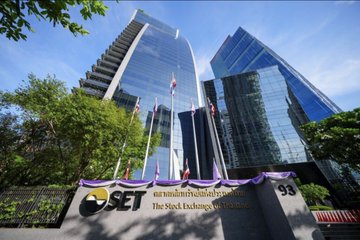 The headquarters of the Stock Exchange of Thailand (SET) is shown, featuring a modern glass facade with the company's golden logo visible at the entrance.
