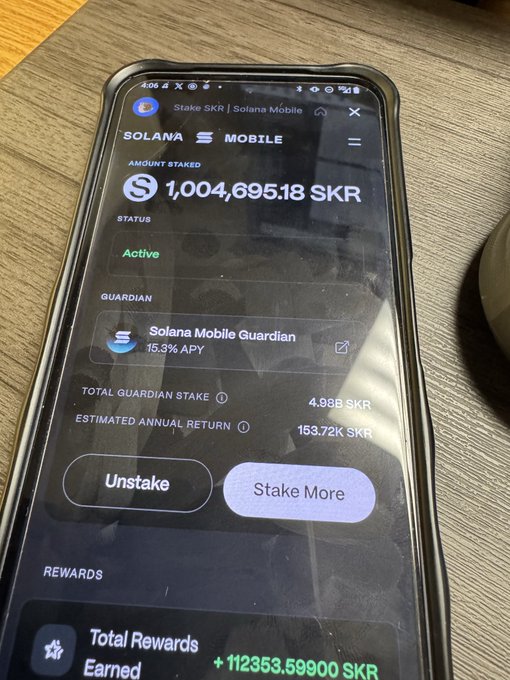A smartphone displays the Solana Mobile app showing an active stake of '1,004,695.18 SKR' with a 15.3% APY and a total reward earned of '+ 112353.59900 SKR'.