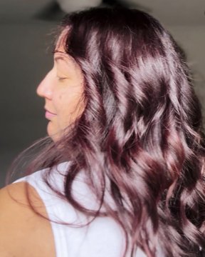 A woman with long, voluminous waves in a rich burgundy/mauve color, shown in profile, representing the "Post Crypto" glow-up after presumably investing in or learning about cryptocurrency.
