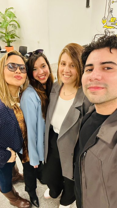 Four people pose for a selfie together indoors, with three women and one man smiling at the camera.